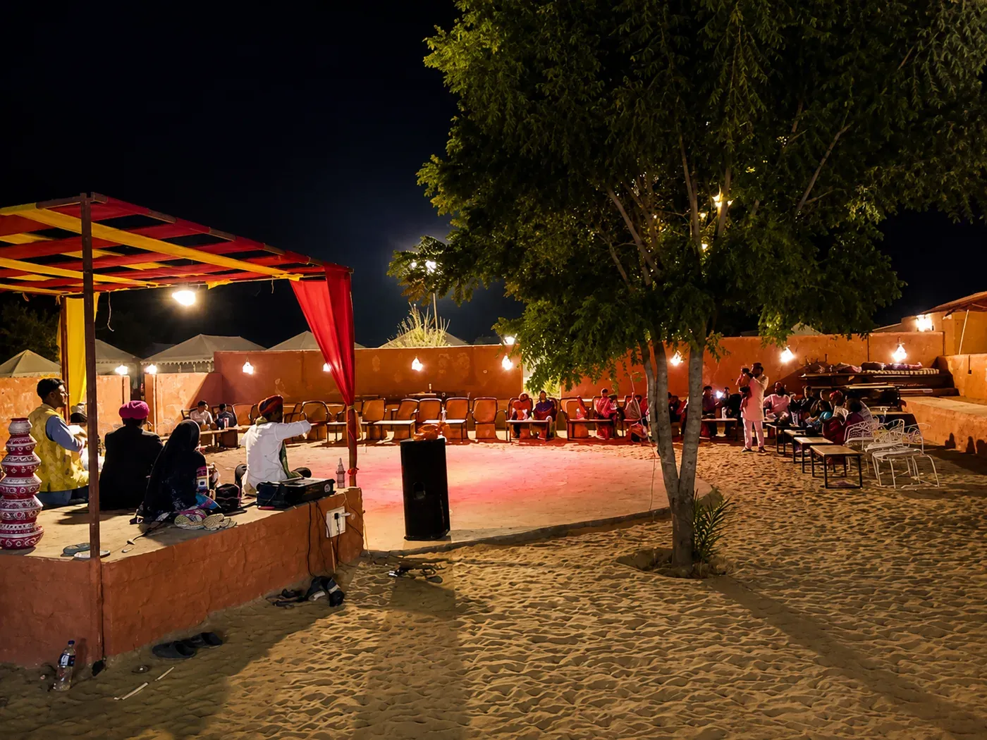 Illuminated open-air desert arena with folk stage and guest seating