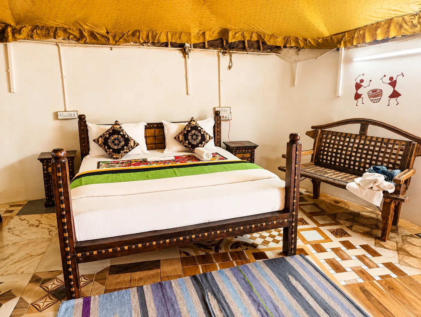Traditional mud cottage bedroom with wooden brass-studded bed and seating bench