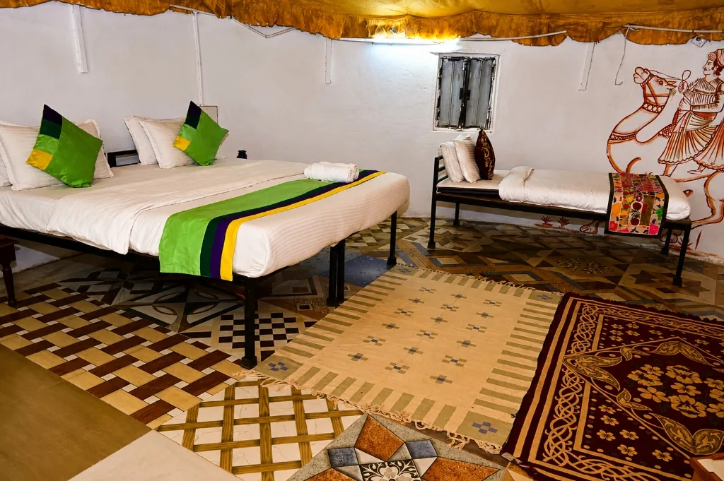 Mud cottage room with traditional Rajasthani wall murals, tiled floors and brass bed