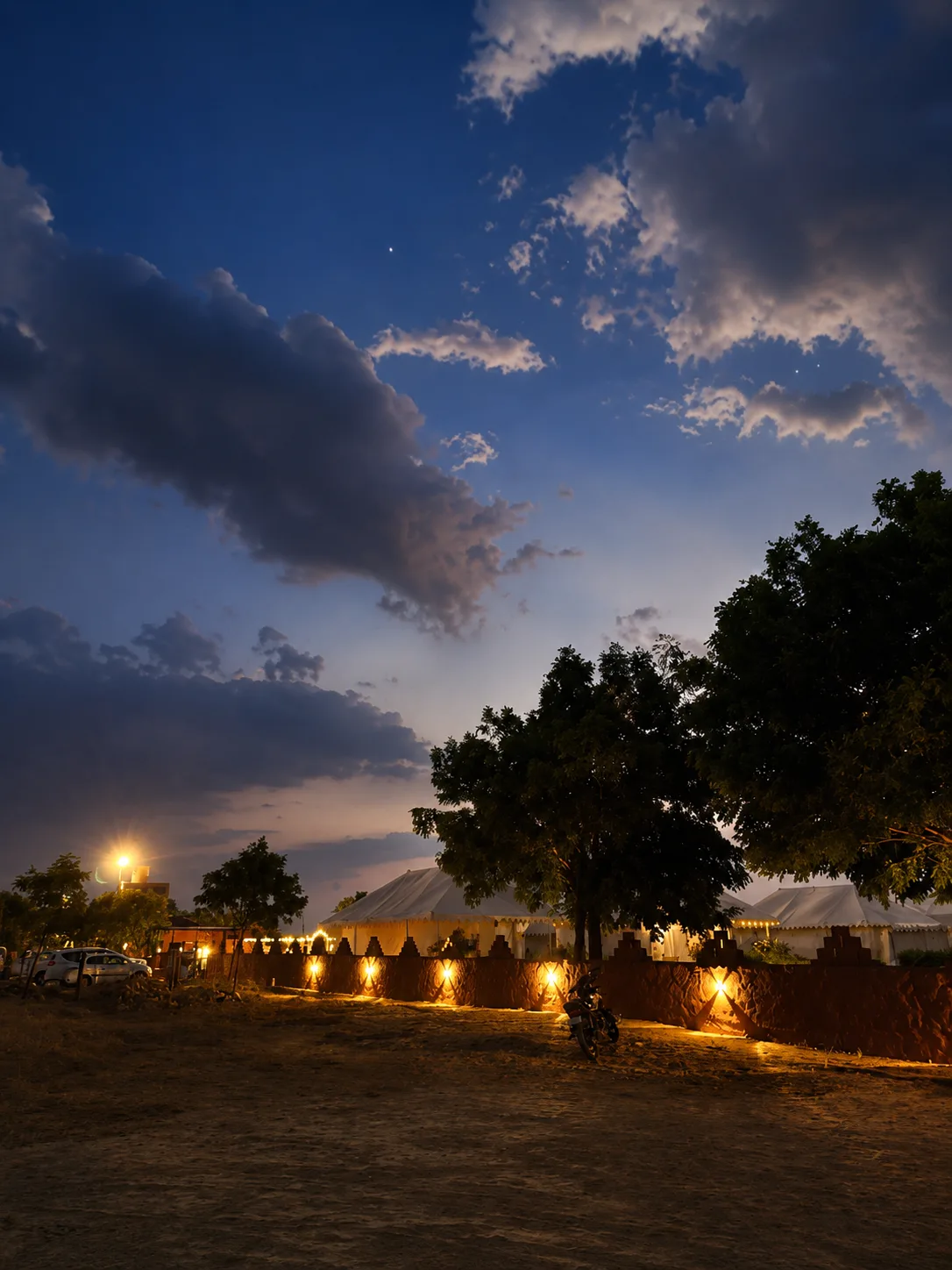 Camp perimeter boundary wall with ambient wall lights under desert sky at dusk