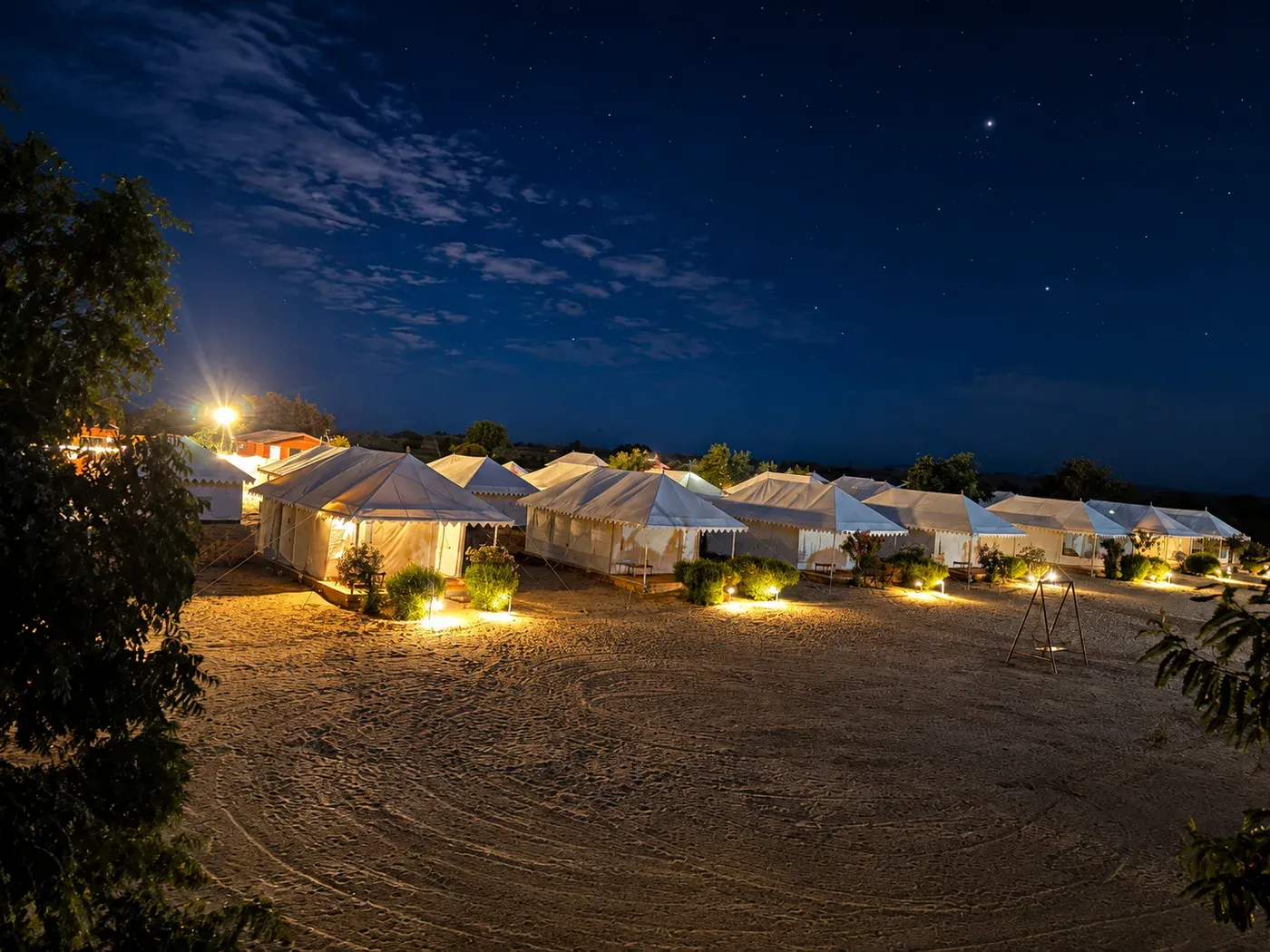 Illuminated Swiss tents row at night under clear desert starry sky