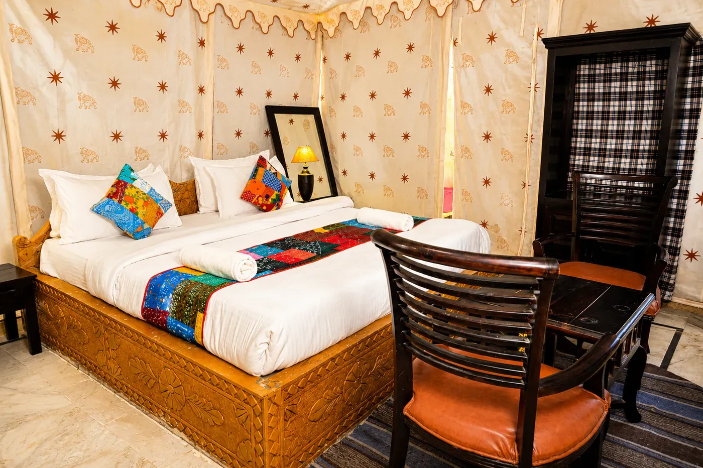 Spacious tent living area with hand-carved wooden seating and wardrobe